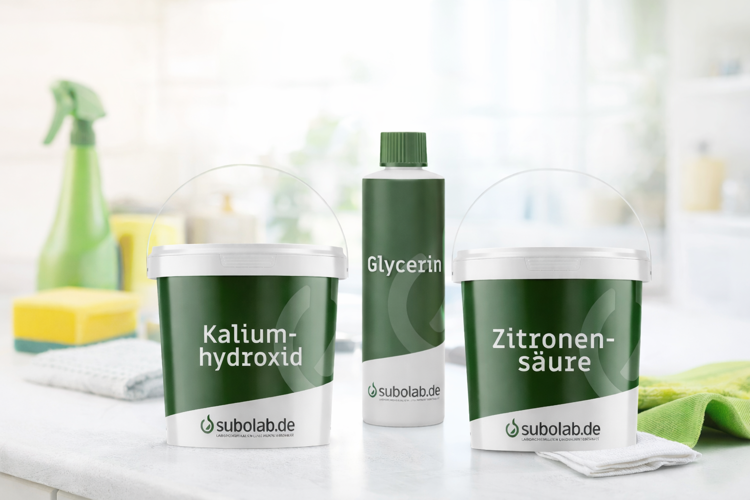 Drei Reinigungsprodukte (Kaliumhydroxid, Glycerin und Zitronensäure) in grünen Verpackungen auf einer Küchenarbeitsfläche, im Hintergrund unscharfe Putzutensilien wie Sprühflasche und Schwämme.